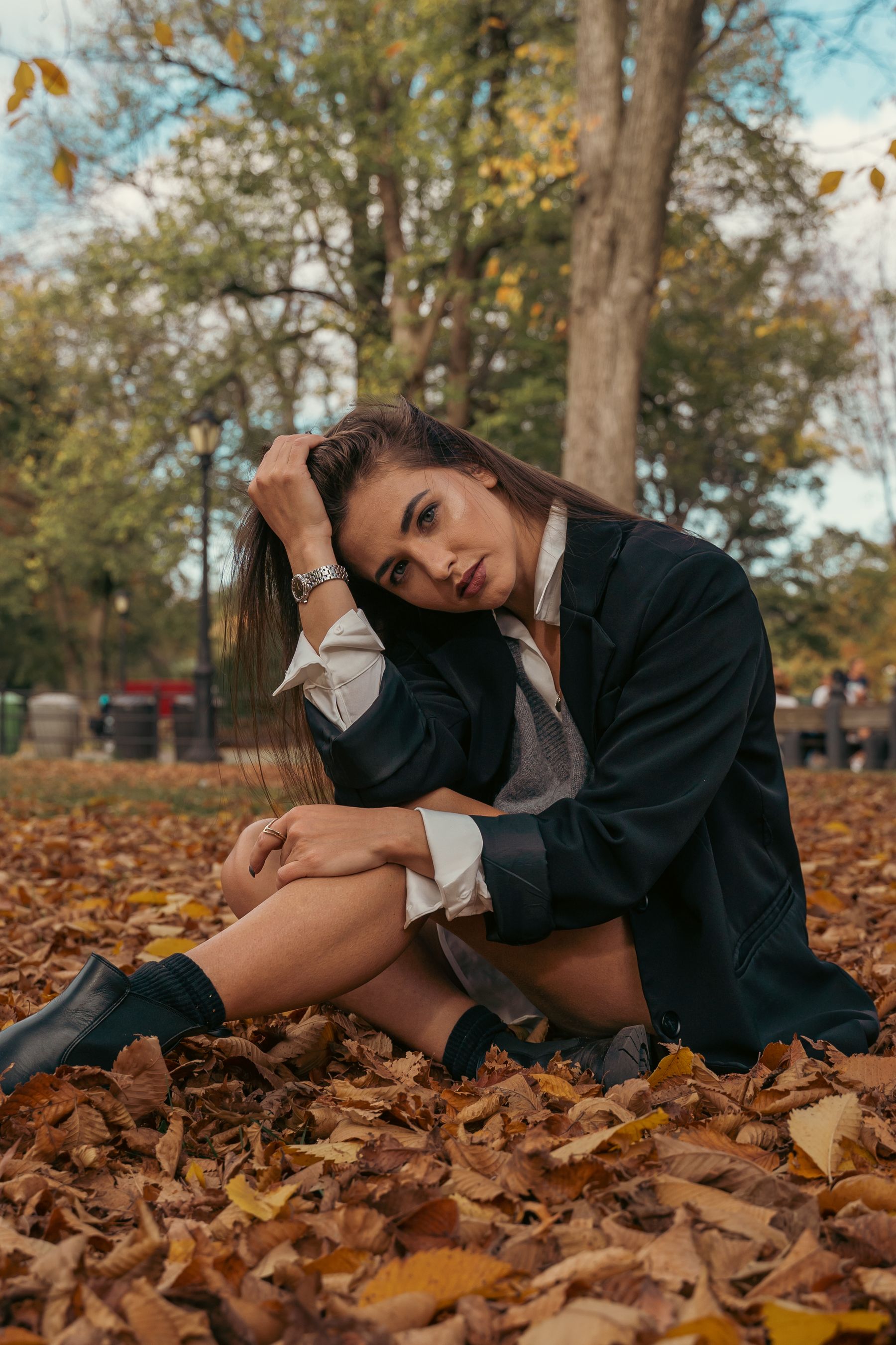 Zwarte enkellaarsjes gedragen bij een blazer tussen herfstbladeren